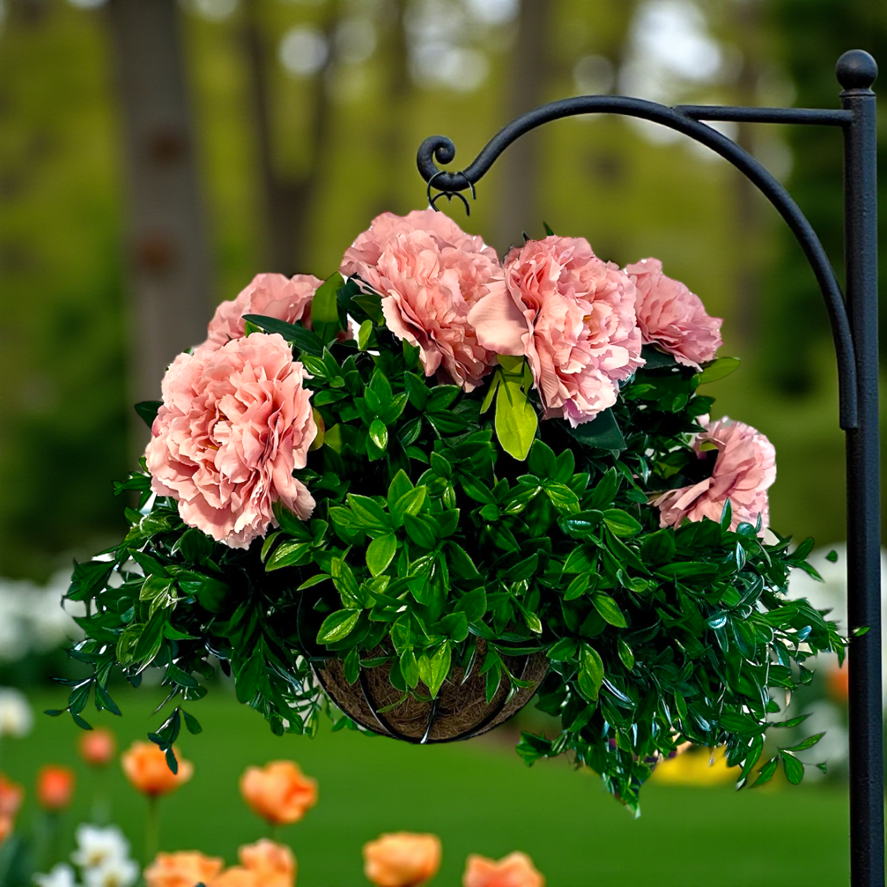 Hanging basket with pink flowers and green leaves against a blurred garden background